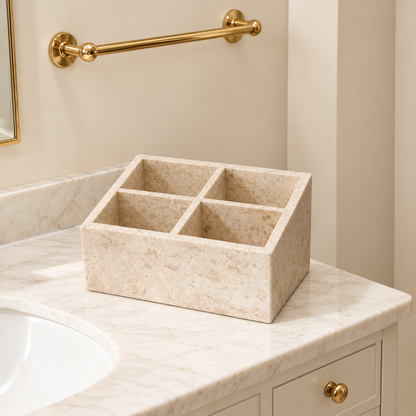 Travertine-style makeup organizer with four compartments on countertop, light beige.