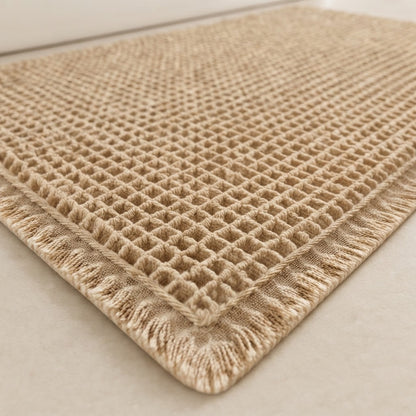 Close-up of khaki waffle bath mat texture with fringed border and non-slip