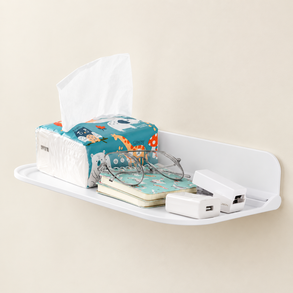 White wall-mounted foldable shelf holding folded items, tissue box, and cable