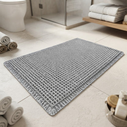 Grey waffle bath mat with fringed border and textured non-slip surface