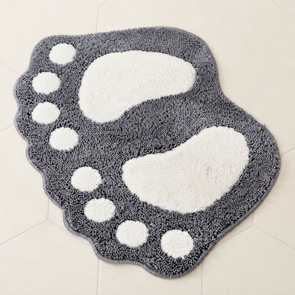 Footprint-shaped bath mat in dark gray shaggy microfiber with white oval and paw-dot accents