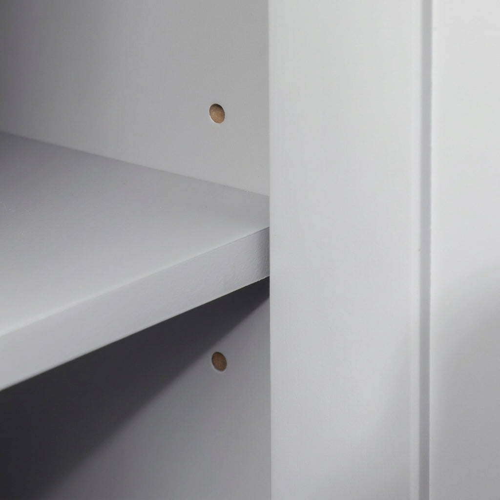Under-sink bathroom cabinet interior with fixed shelves and two round wall-mount holes