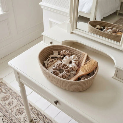 Oatmeal woven cotton rope oval storage basket on a dresser, open top