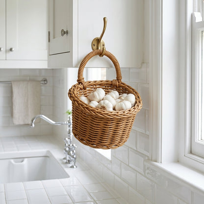 Dark tan woven hanging storage basket holding white eggs with loop handle and hook.