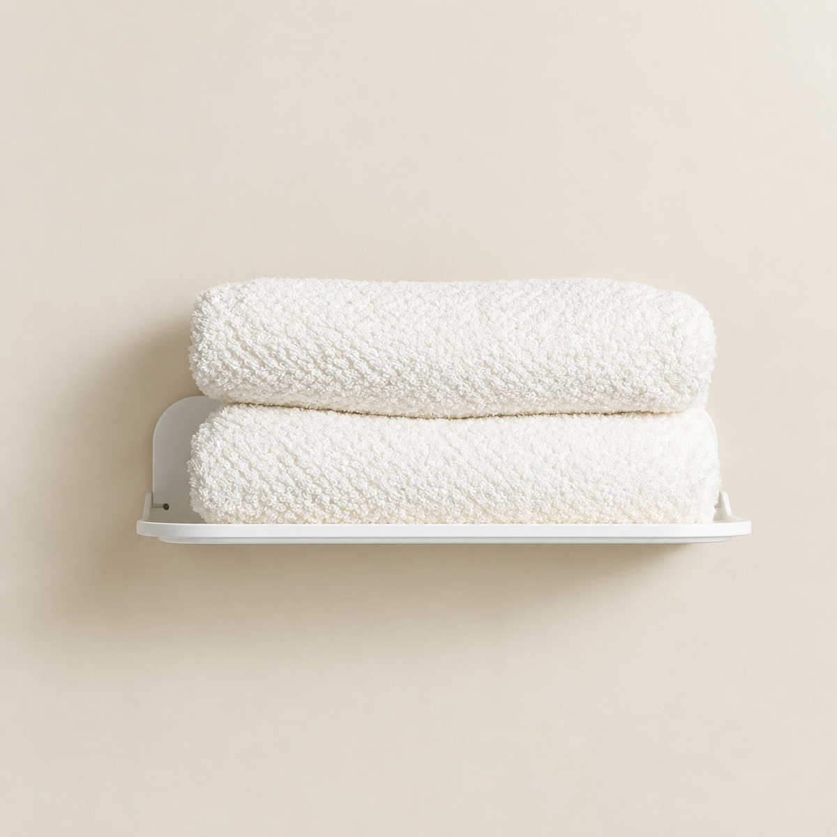 White wall-mounted foldable shelf with two folded towels stacked on top