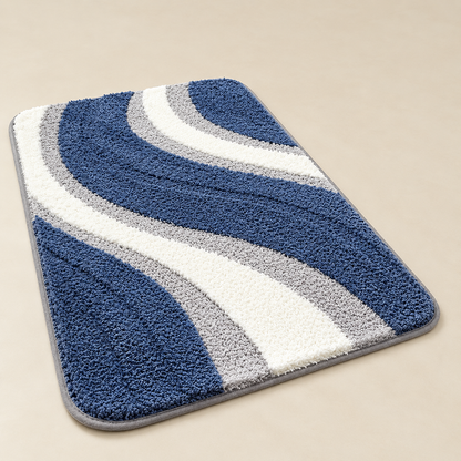 Tufted wave stripe bath mat with blue and white loops, non-slip backing, rounded edges.