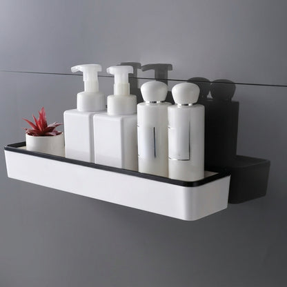 Wall-mounted bathroom storage shelf with white body and black trim, toiletries on top
