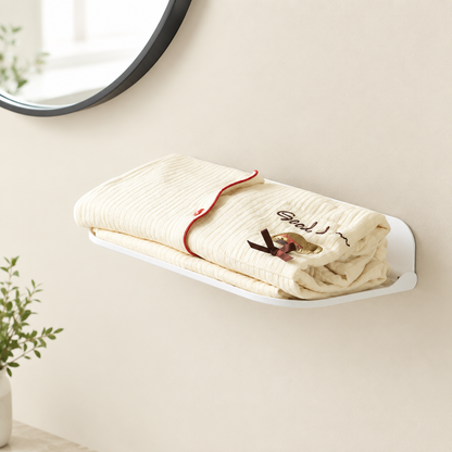 White foldable wall shelf with a folded towel stacked on the shelf