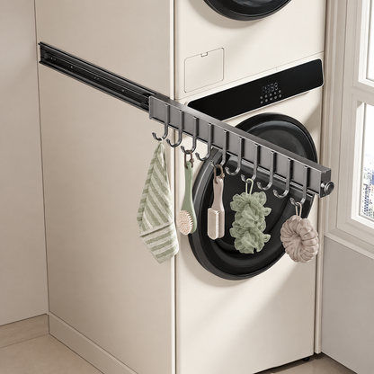 Dark sliding hook rail with curved hooks holding towels and loofahs by washer