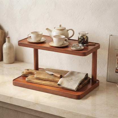 Light brown bamboo two-tier shelf holding teacups, a teapot, and small bowls.
