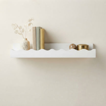 White wooden floating wall shelf with scalloped edge, styled with small books and vase