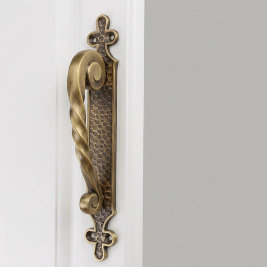 Twisted bow brass door pull with textured base and decorative cross plates, dark bronze