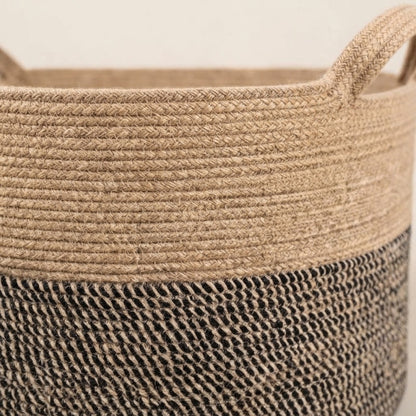 Close-up of woven cotton rope basket, tan top rim and dark striped lower section.