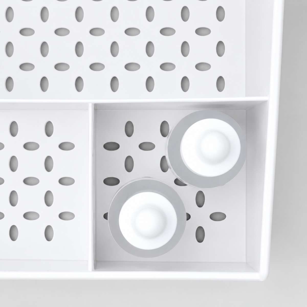White makeup organizer grid with circular compartments and round accessory holders
