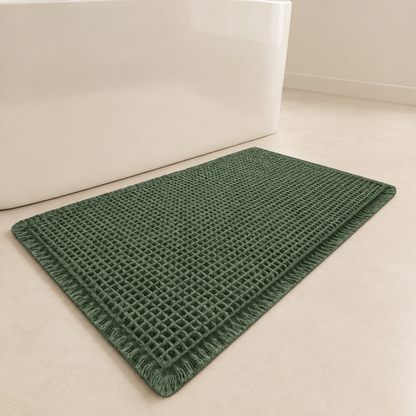 Green waffle bath mat with fringed corners and non-slip backing