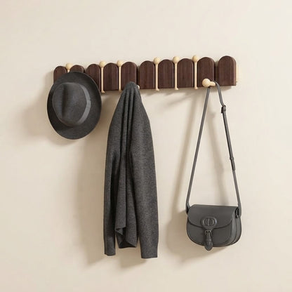 Solid wood arched coat rack with light gold knobs holding a hat, jacket, and bag