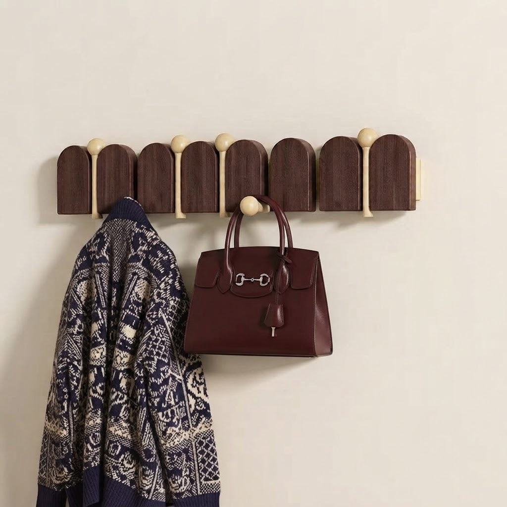 Solid wood arched coat rack with light gold knobs holding a patterned jacket and handbag