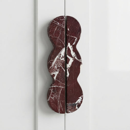 Wavy red marble cabinet handle with white veining and vertical split bar
