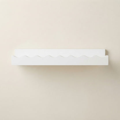 White wooden floating wall shelf with scalloped front edge and smooth underside