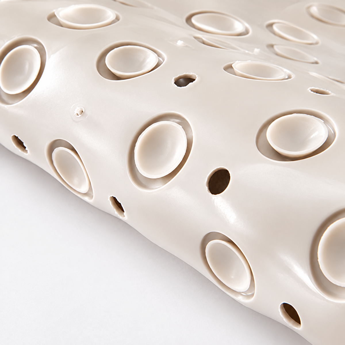 Textured non-slip shower mat surface with oval scrub area and drainage holes