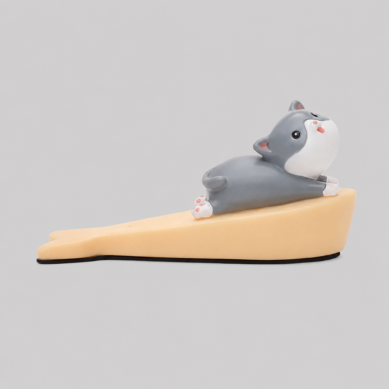 Cat-shaped door stop, gray and white on beige base with black edge.
