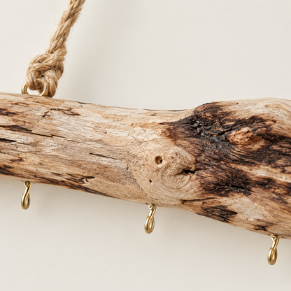 Close-up of driftwood multi-hook rail with dark wood marks and gold loop hooks