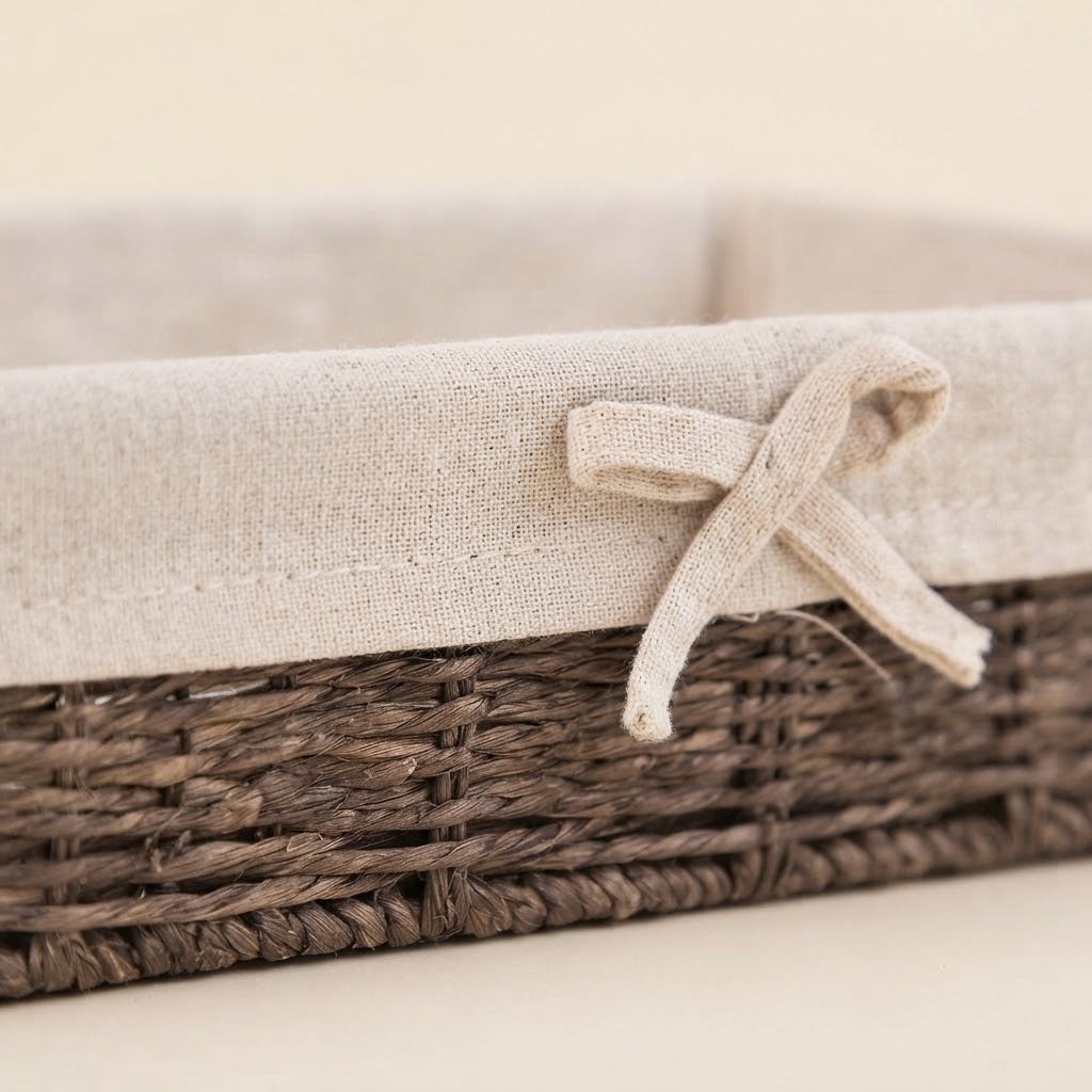 Dark woven willow straw storage basket with beige fabric liner and tied bow