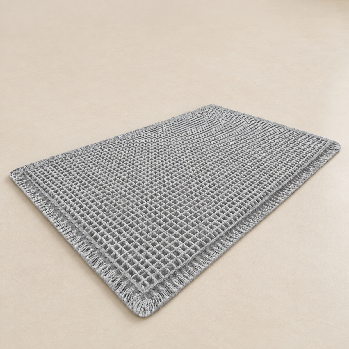 Grey waffle bath mat with fringed edges and non-slip backing