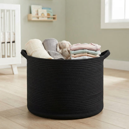Black woven rope storage basket with rounded handles, holding folded baby items.