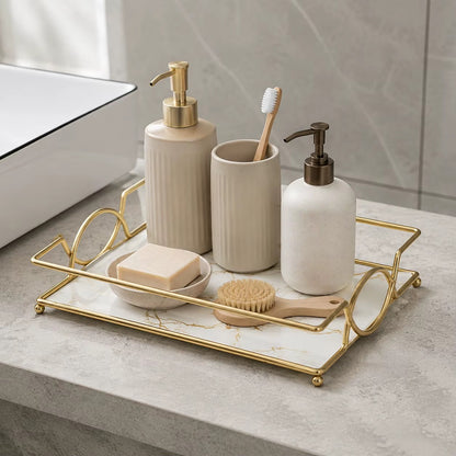 Gold vanity tray with marble-effect surface for soap, bottles, and a cleaning brush
