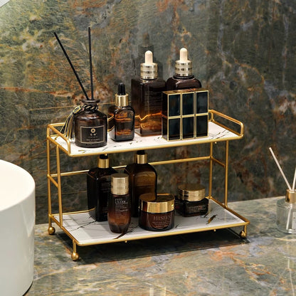 2-tier bathroom organizer with gold frame and skincare bottles on white marble-look trays