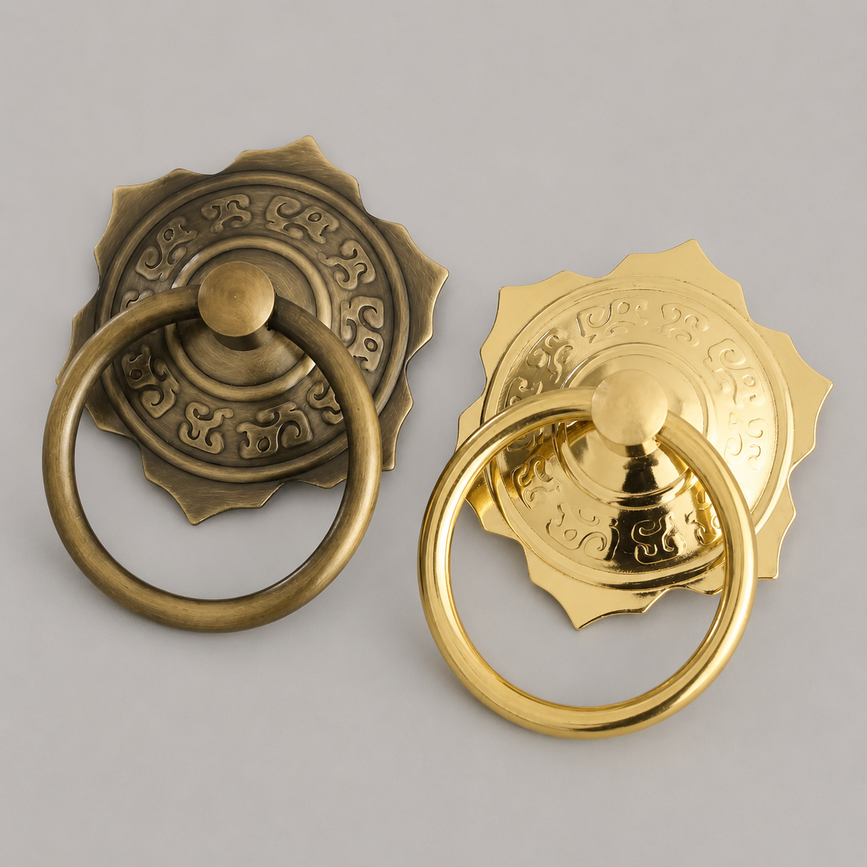 Pair of brass pull ring door knockers in bronze and gold with ornate rosettes