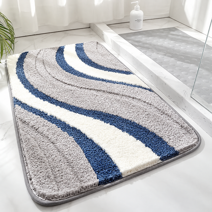 Tufted wave stripe bath mat with gray, blue, and white bands on non-slip backing.