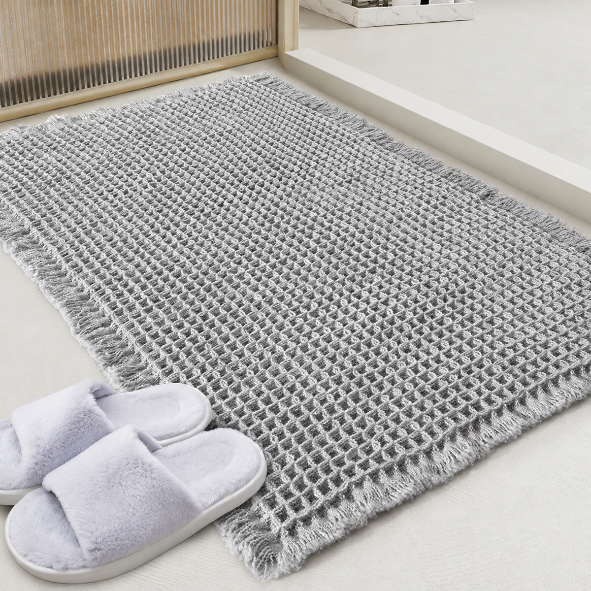 Grey waffle bath mat with fringed edge and non-slip backing