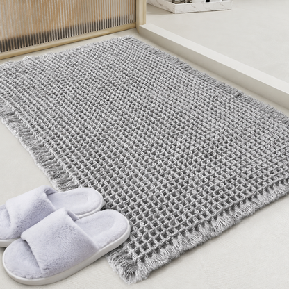 Grey waffle bath mat with fringed edge and non-slip backing