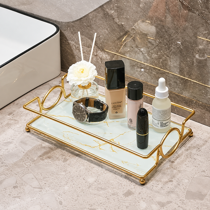 Gold vanity tray with marble-effect insert displaying skincare bottles and beauty accessories