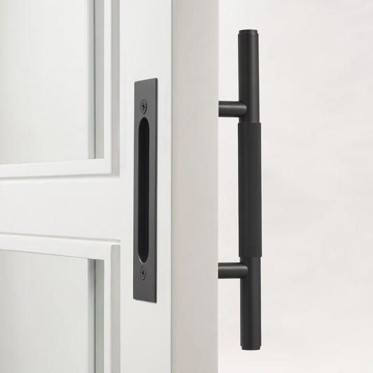 Black sliding door handle on door panel with vertical pull bar and mounting plate
