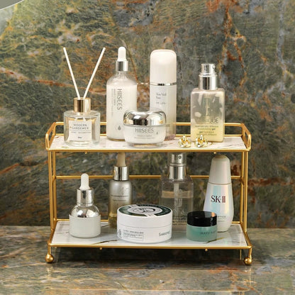 2-tier bathroom organizer with gold frame holding skincare bottles on white marble-look trays