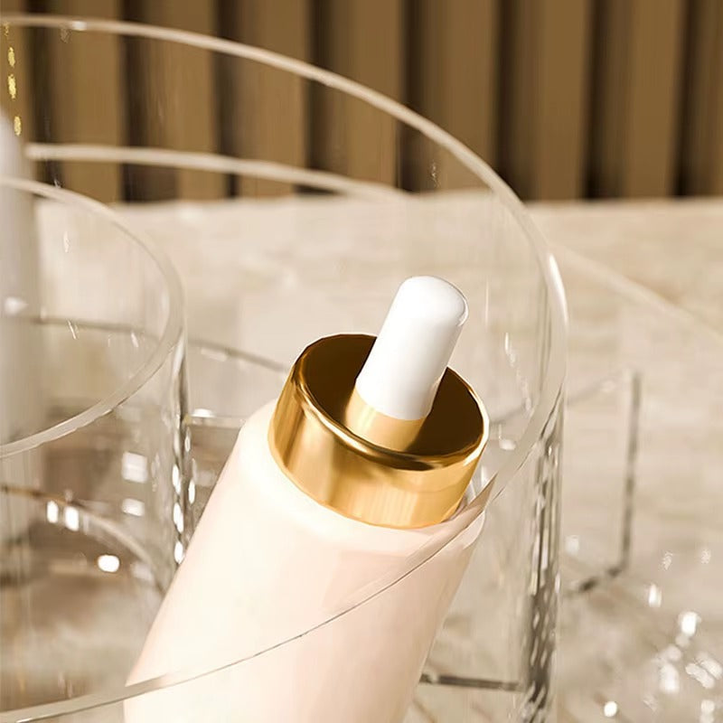 Close-up of clear acrylic makeup organizer tier with gold holder and white cap