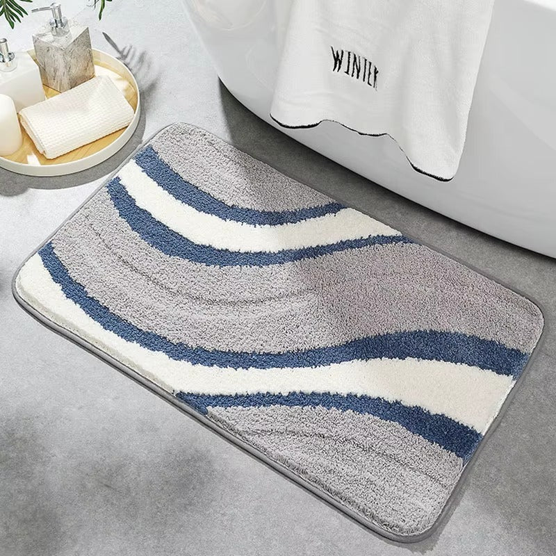 Wave stripe bath mat with gray base, blue and white curved bands, non-slip border.
