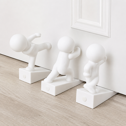Three white playful character door stops leaning against a wall, each on a rectangular base