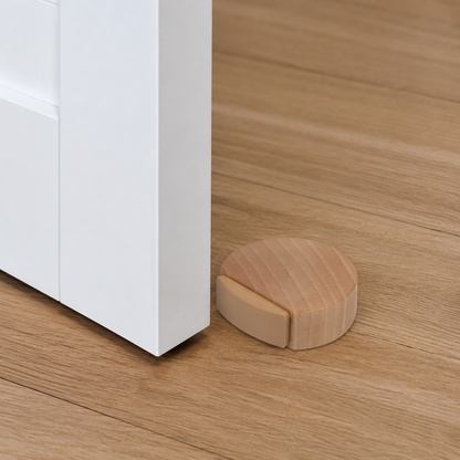Low-profile wooden self-adhesive door stop installed on a wood floor