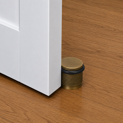 Brass knurled door stop installed at door base with black rubber ring