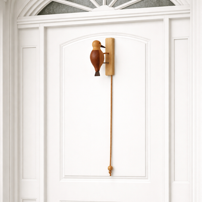 Wooden woodpecker door knocker mounted on a door with wooden pull cord