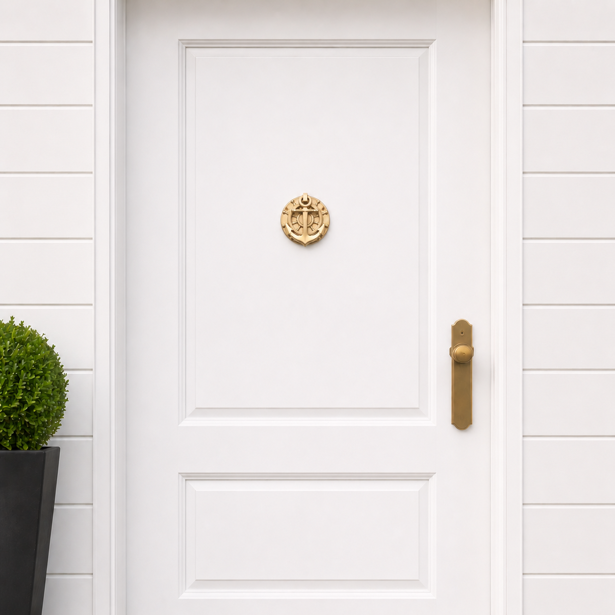 Brass nautical anchor door knocker mounted on a white door with circular helm and cross